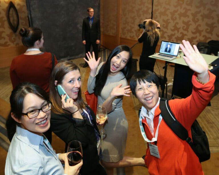 Attendees waving while they wait in line for a convention headshot station