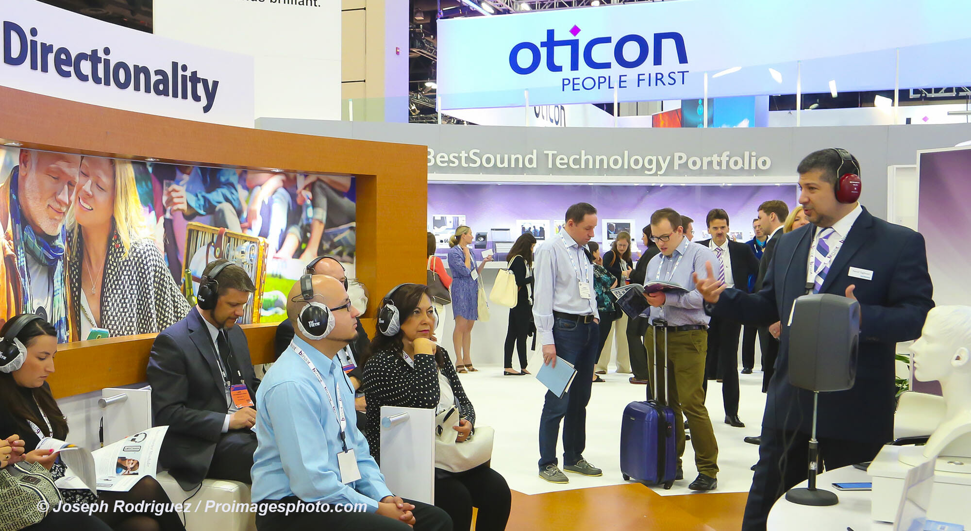 Tradeshow Photography of attendees listening to presenter in Tradeshow Booth.