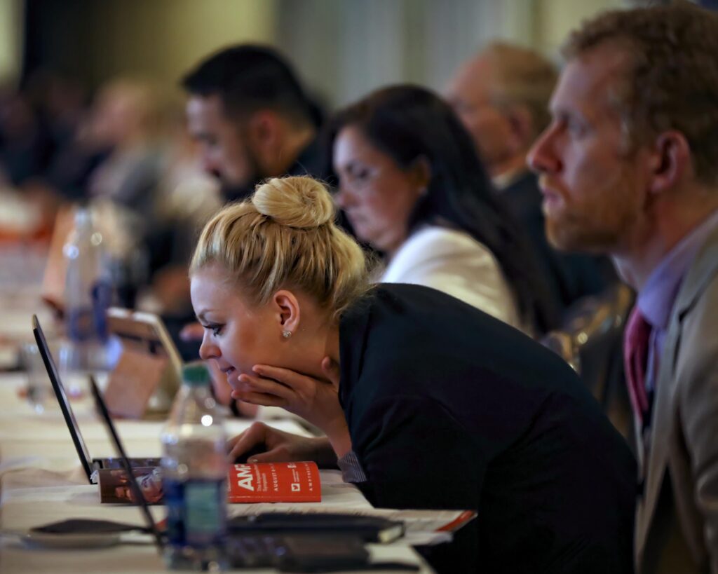 Attendee reviewing a laptop during a presentation at AMP Clinical's annual meeting, Chicago Hilton, convention photography