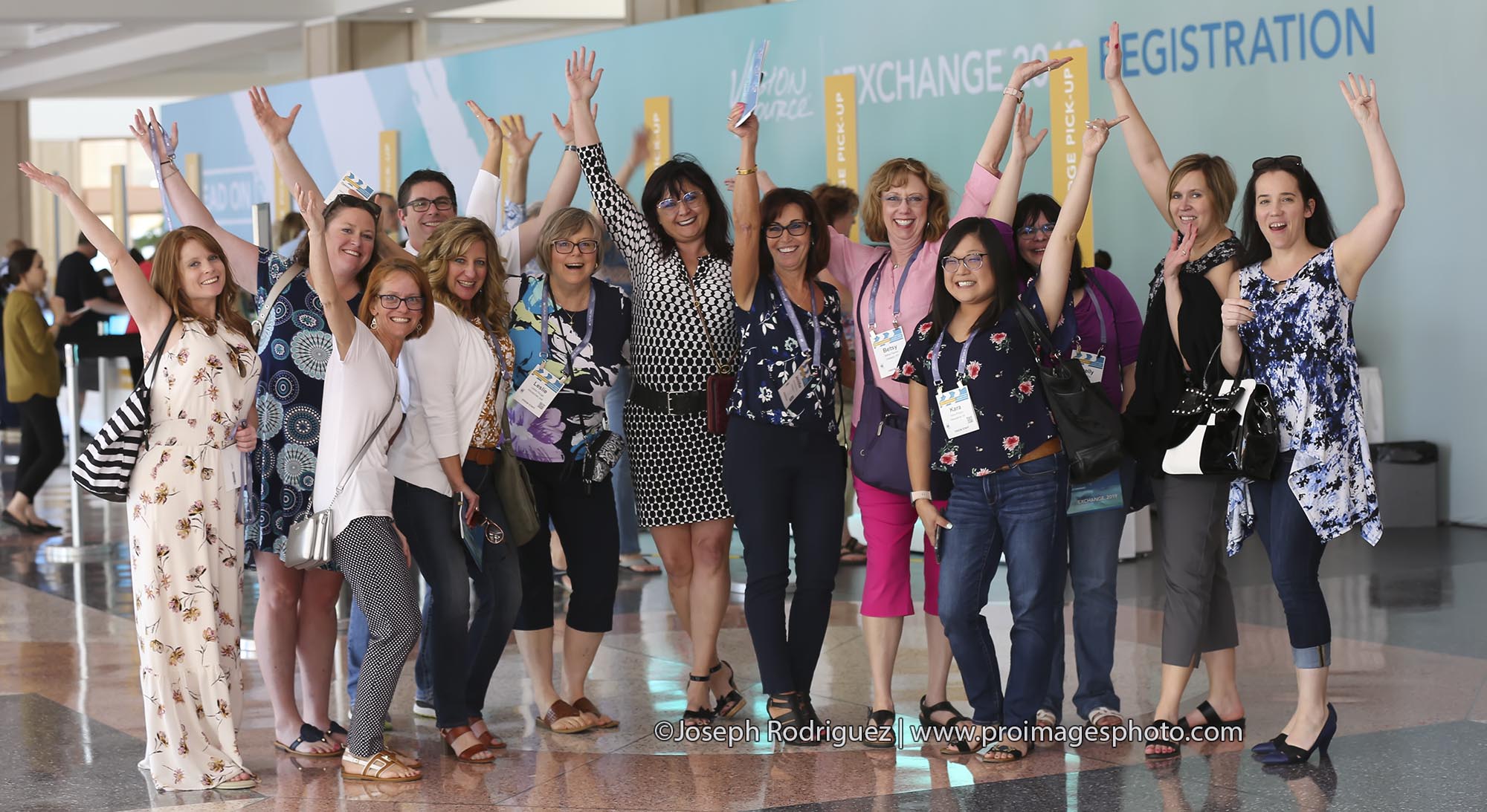 Houston, Texas convention photography of attendees celebrating with arms raised beside conference registration.