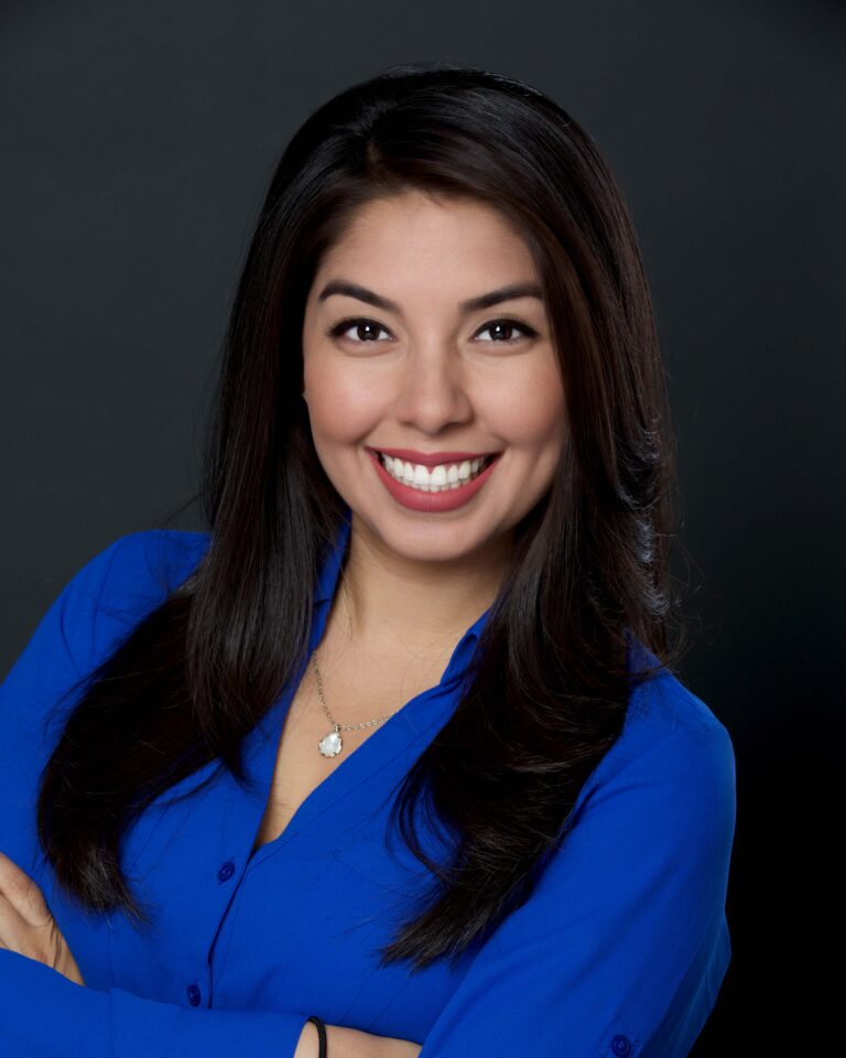 Finished headshot of a smiling woman in a blue blouse on a dark backdrop
