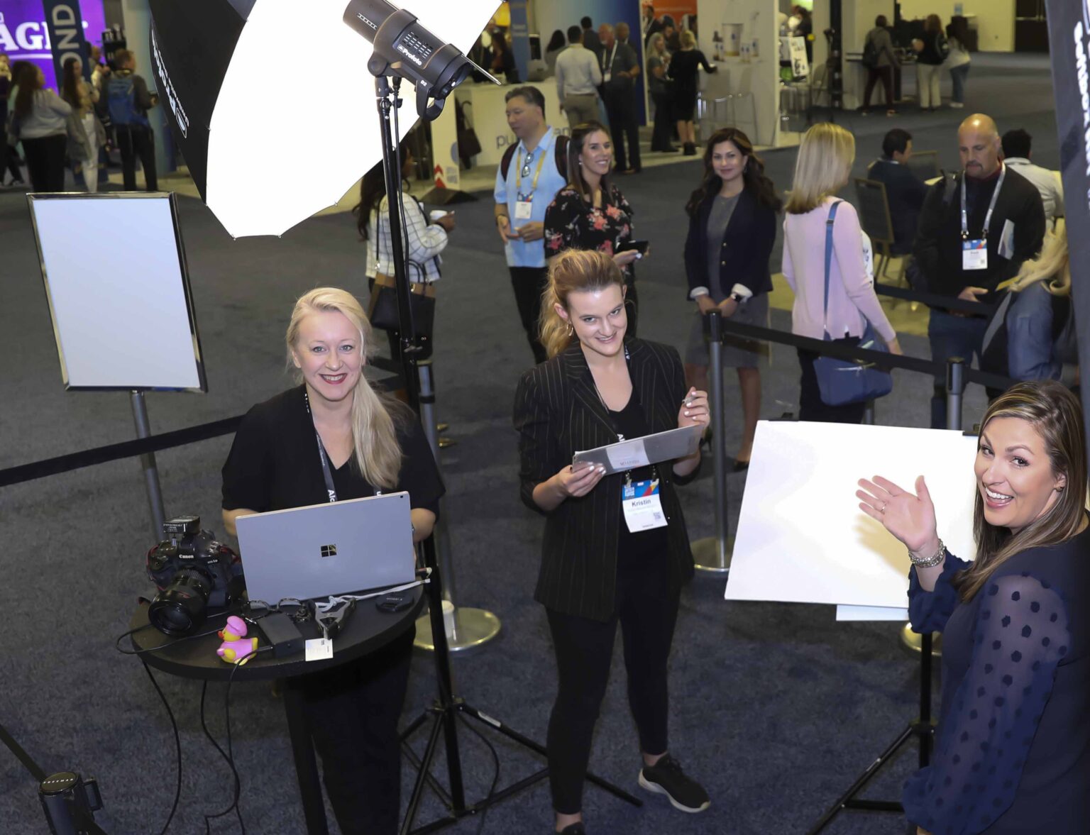 Headshot station team with a tethered laptop at a convention, attendees lined up for professional headshots