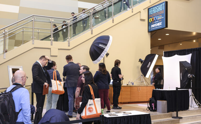 Sponsored headshot photo studio in a convention center concourse, attendees lining up for headshots